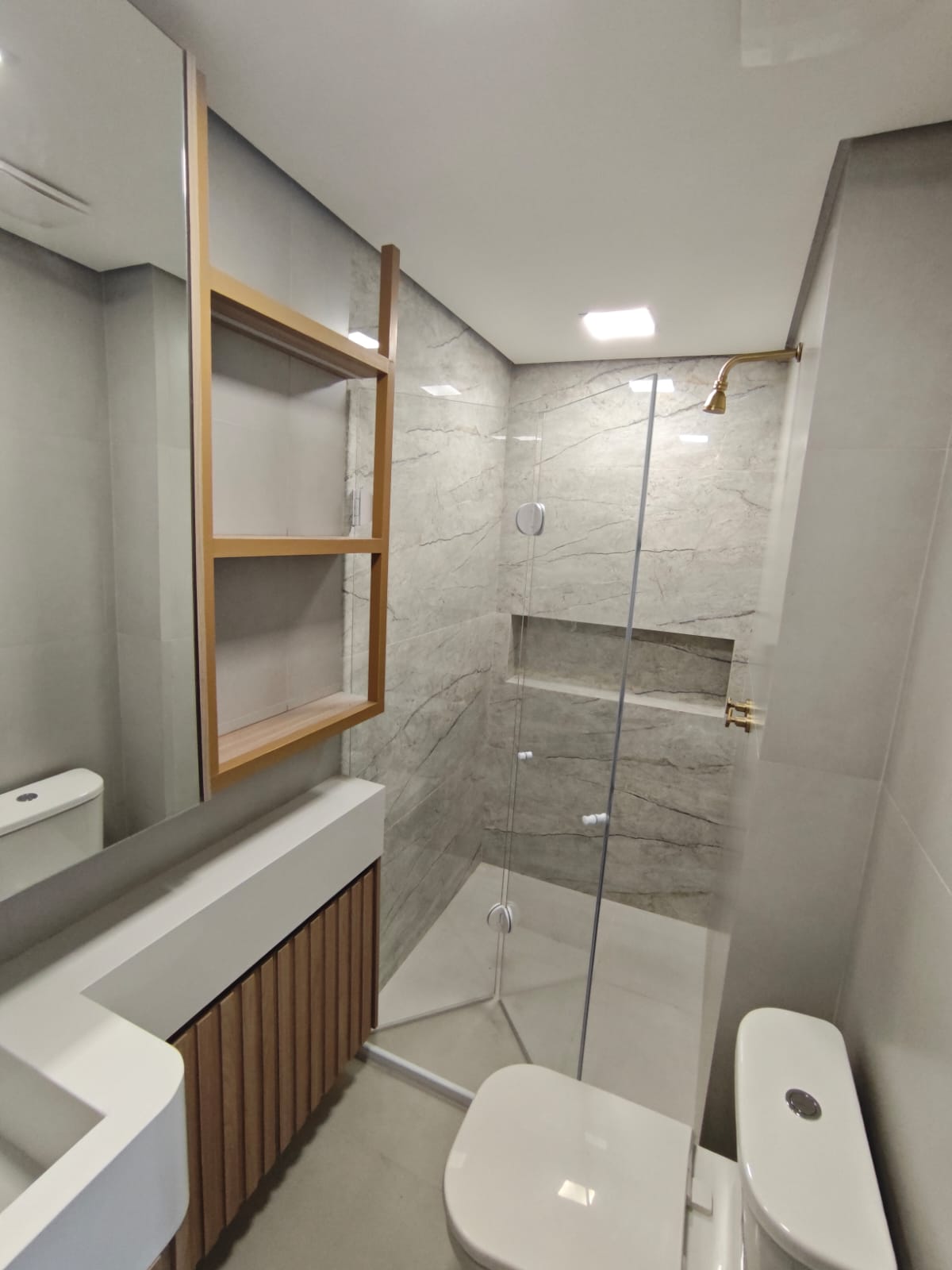 uma foto de um banheiro moderno com banheira de chuveiro de vidro, pia e toilette — texto: