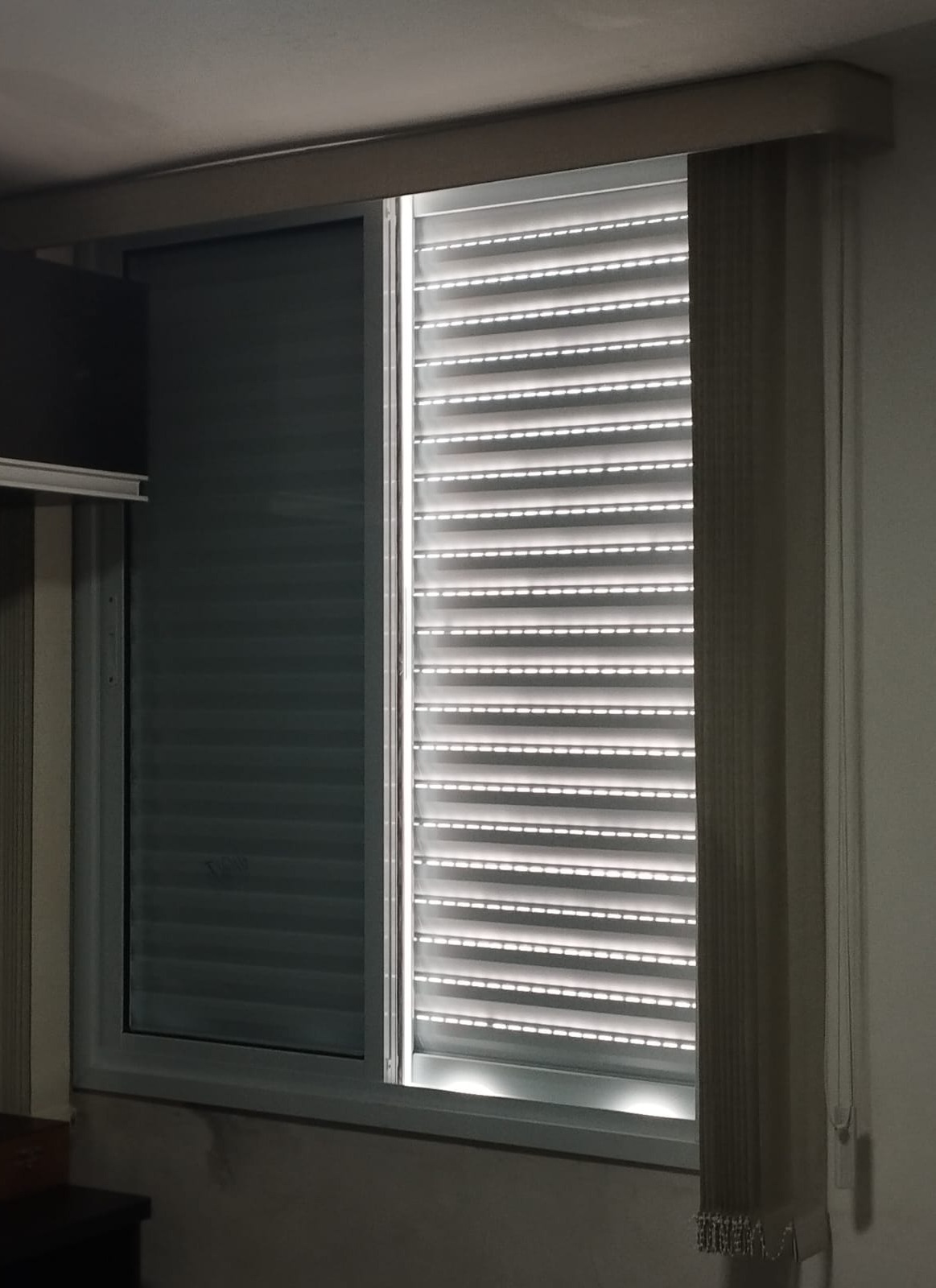uma janela com cortina e lousa, parte da janela com luz de fora, outro lado com lousa opaca, em um quarto inte