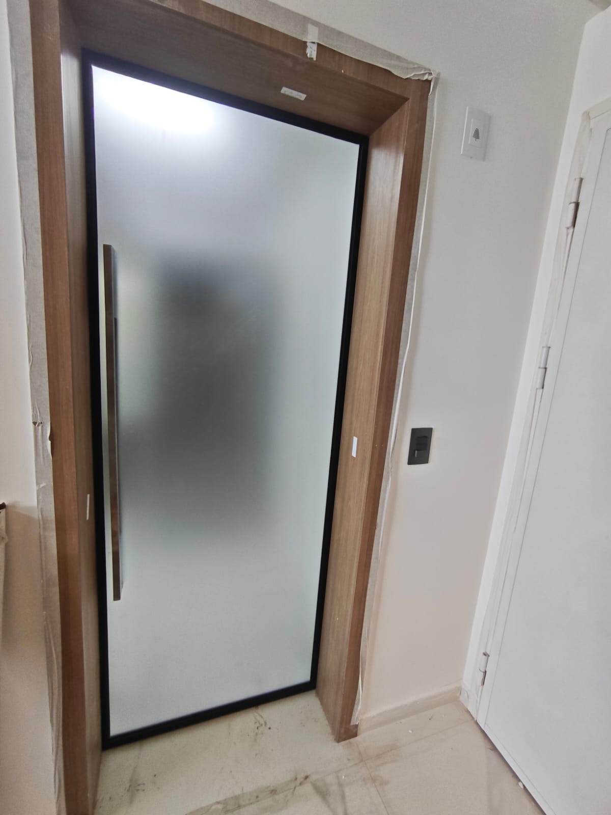uma porta de entrada com vidro opaco e moldura de madeira em um ambiente interno